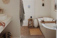 11 a boho bathroom clad with stacked tiles, an oval tub, some boho rugs, a woven pendant lamp and a vanity