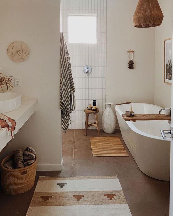 a boho bathroom clad with stacked tiles, an oval tub, some boho rugs, a woven pendant lamp and a vanity