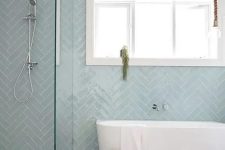 12 a contemporary bathroom with dusty blue herringbone tiles, an oval tub, a shower, a basket and a stool is welcoming