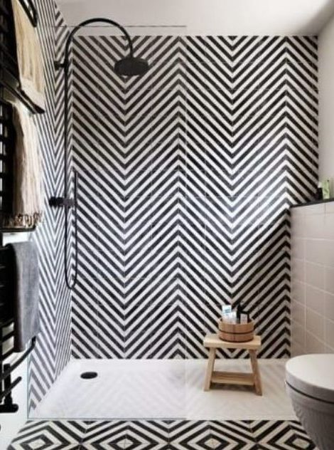 a bold black and white bathroom with herringbone patterned tiles and geometric ones on the floor plus black fixtures