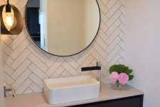 16 a sink zone with white herringbone tile, a built-in vanity, a round mirror and a pendant lamp is a cool and minimal space