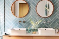 20 a chic bathroom with blue herringbone tiles, a stained vanity, mirrors and sinks is a lovely space