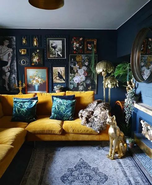 a navy maximalist living room with a yellow sofa and colorful pillows, a bold gallery wlal and a fireplace, some gilded decor