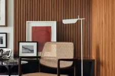 21 a mid-century modern living room with stained wood slat accent walls, a rattan chair, a black table and bright artwork