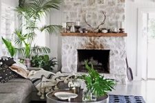 23 a chic monochromatic living room with a whitewashed stone fireplace, a wooden mantel with candles and antlers and potted plants