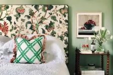 23 a cool and chic bedroom with green walls, a bed with a floral headboard, neutral bedding and a green bedspread, a nightstand and white blooms