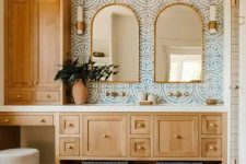 24 a Mediterranean bathroom with blue printed tiles, a terracotta tile floor, stained cabinets and arched mirrors