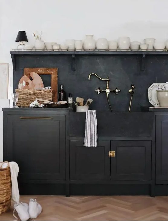 a black shaker style kitchen with black soapstone countertops and a backsplash, an open shelf to display beautiful vases