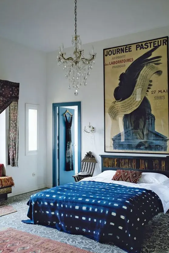 An eclectic bedroom with a dark stained bed and printed bedding, patterned rugs and curtains and a large poster