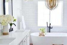 26 a modern farmhouse bathroom with white tile walls and a terracotta hex tile floor, a whitewashed vanity, an oval tub and greenery