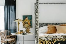 26 an eye-catchy bedroom with a printed bed and bedding, printed rugs, art, a rattan chair and some pillows