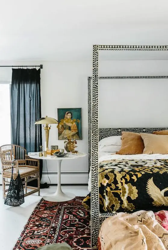 An eye catchy bedroom with a printed bed and bedding, printed rugs, art, a rattan chair and some pillows