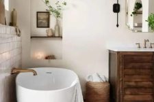 27 a modern rustic bathroom with white plaster walls and a terracotta tile floor, a stained vanity, an oval tub and greenery
