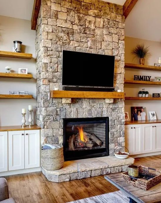 a cozy neutral living room spruced up with a stone fireplace, a wooden mantel and a TV over the fireplace