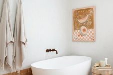 29 a whimsical bathroom with white and terracotta tiles, an oval tub, a side table, a bold artwork