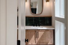 31 a modern bathroom with terracotta and green skinny tiles, a brushed vanity, mirrors in frames and wall lamps