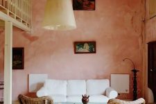 32 a beautiful living room with pink limewashed walls, a white sofa, woven chairs, a delicate table and a pendant lamp