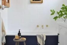 36 a stylish modern bathroom with blue Moroccan tiles, a bathtub clad with navy tiles, a cabinet, an artwork and a white vanity