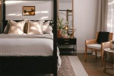 37 a welcoming neutral bedroom done with a black canopy bed, a chair, a black nightstand, layered rugs and a beaded chandelier
