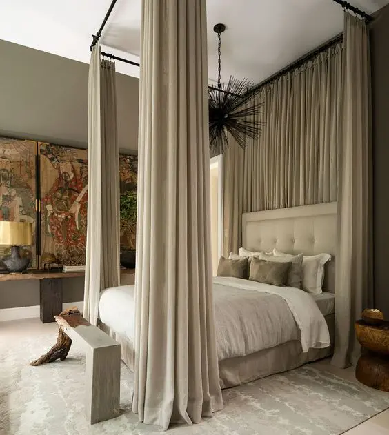 a sophisticated neutral bedroom with an upholstered bed and neutral bedding, a bench, a console table and bold artwork
