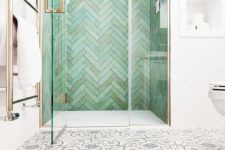39 a creative bathroom with patterned tiles on the floor and an attic shower space clad with green herringbone tiles