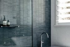 40 a contrasting bathroom with white stacked and dark green skinny tiles, an oval tub and a shower space