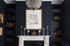 40 a moody navy living room with a fireplace, built-in shelves, a navy and a plaid sofa, a crystal chandelier