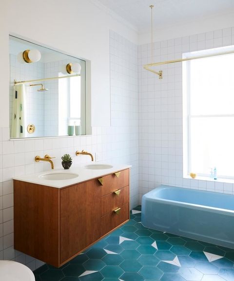A mid century modern bathroom clad with white square and blue hex tiles, a stained vanity, a blue bathtub