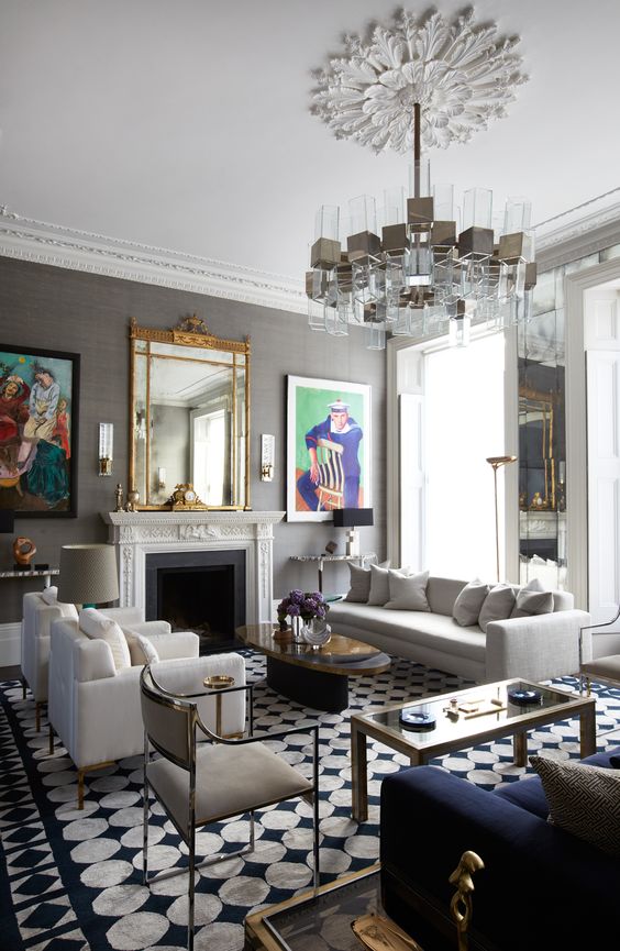 an eclectic living room with a fireplace, a sofa and chairs, coffee tables and a unique chandelier over the space