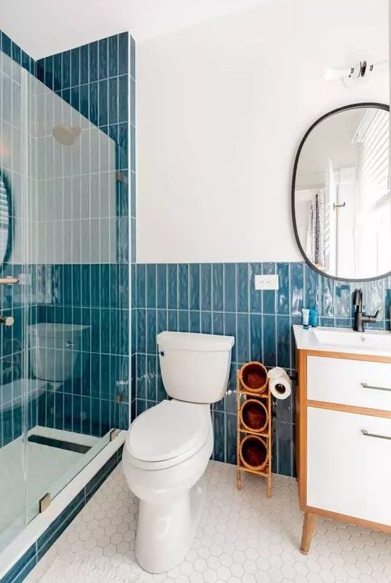 a catchy modern bathroom with bold blue stacked tiles, white hex tiles on the floor, a neutral vanity and white appliances