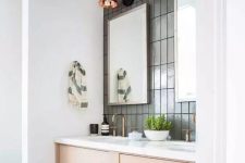 47 a modern bathroom with grey stacked skinny tiles, a blonde wood vanity with a white countertop, brass fixtures and copper sconces