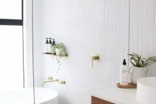 48 a serene Scandinavian bathroom with white stacked tiles, a stained timber vanity, an oval tub and gold fixtures