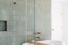51 a modern bathroom with a geo floor, a green stacked tile wall, an oval tub and brass fixtures