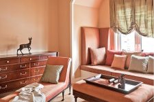 a Peach Fuzz vintage living room with a windowsill sofa, a large ottoman, a coral daybed and a rich-stained console