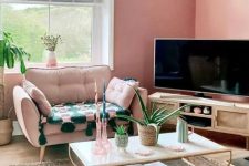 a Peachy Fuzz living room with a TV on a TV unit, a pink chair, a green sofa, a tiered coffee table and a printed rug