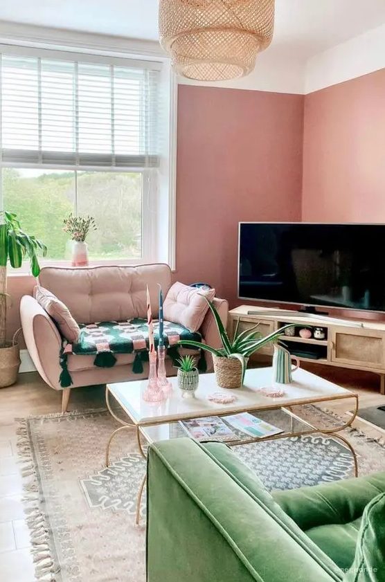 a Peachy Fuzz living room with a TV on a TV unit, a pink chair, a green sofa, a tiered coffee table and a printed rug