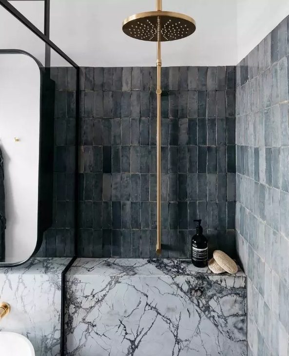 a bathroom with grey skinny Zellige tiles stacked, white marble and brass fixtures is an amazing contemporary space
