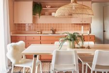 a beautiful Peach Fuzz kitchen with peachy and coral cabinets, a square tile backsplash, countertops and open shelves and a white dining zone