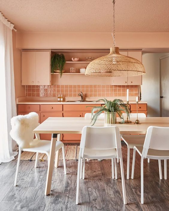 a beautiful Peach Fuzz kitchen with peachy and coral cabinets, a square tile backsplash, countertops and open shelves and a white dining zone