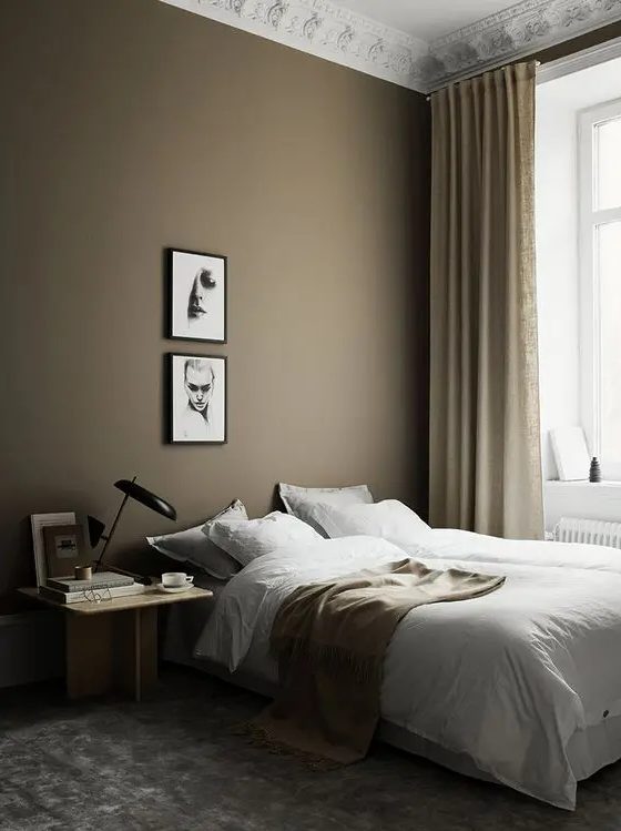 A beautiful Scandi bedroom with a taupe accent wall, a bed, a light stained nightstand, a mini gallery wall and tan and gold touches