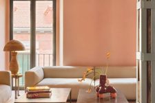 a beautiful contemporary living room in peachy tones, with a creamy low sofa, coffee tables and a table lamp