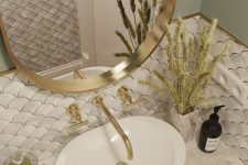 a beautiful sink space with white scallop tiles, a marble vanity, a sink, an oval mirror and gold touches