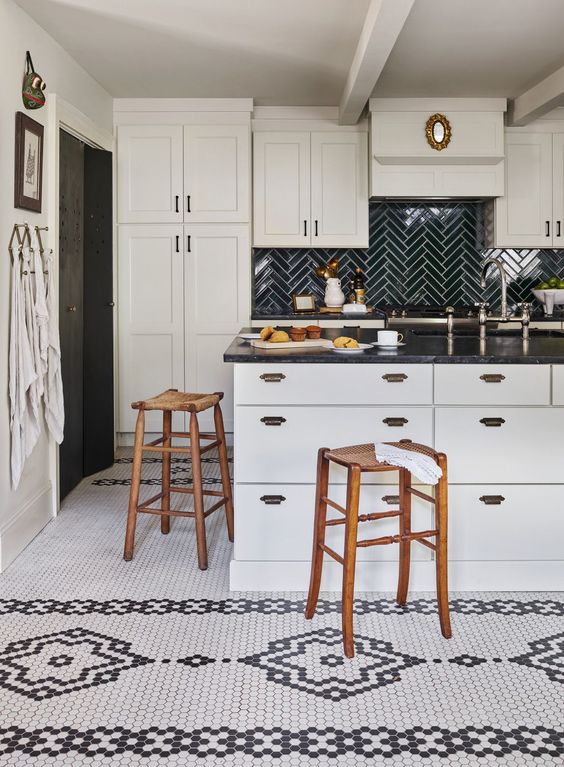 a black and white kitchen with shaker and sleek cabinets, black countertops, a black herringbone tile backsplash, a black and white tile floor