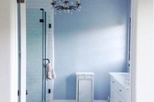 a blue and white bathroom with navy fishscale tiles on the floor, an elegant chandelier and white furniture looks sea-like