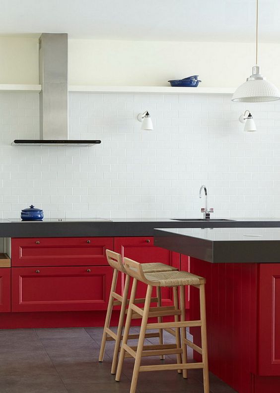 a bold and contrasting kitchen with lower red cabinets and statement countertops, a white tile backsplash and pendant lamps