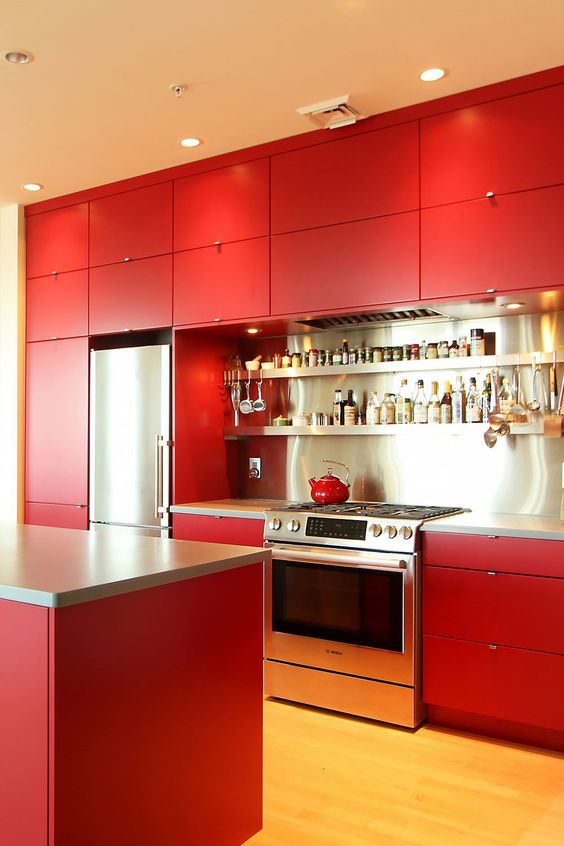 A bold red kitchen with matte cabinets, a stainless steel backsplash and shelves and built in lights