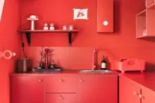 a bold red solid kitchen with chic cabinets, shelves, backsplashes and countertops is completely red and statement-like