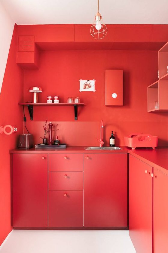 A bold red solid kitchen with chic cabinets, shelves, backsplashes and countertops is completely red and statement like