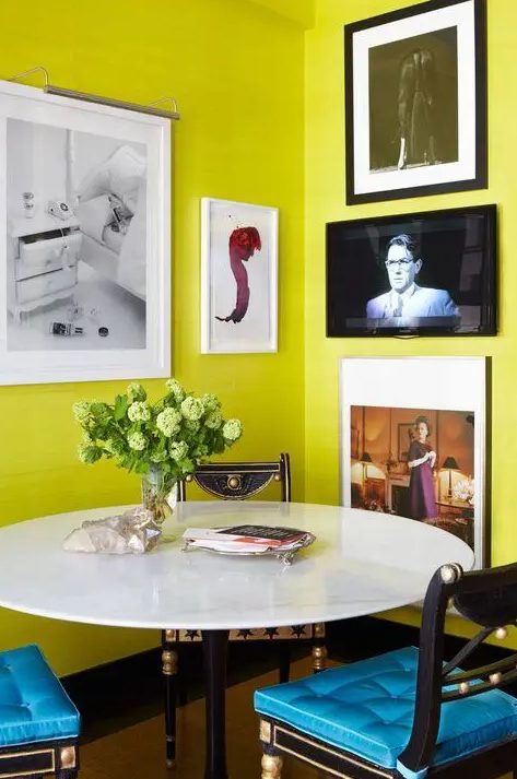 a bright dining nook with chartreuse walls, a round table and mismatching chairs, a corner gallery wall