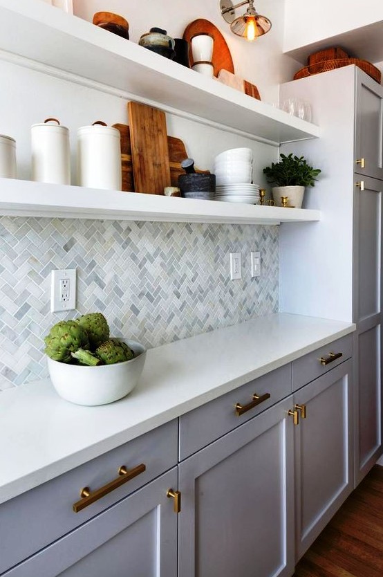 a catchy modern white kitchen with a marble tile backsplash, open shelving and touches of gold for more chic and elegance
